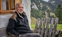 Herzog, seated outside a chalet  with mountains behind in a scene from Werner Herzog: Radical Dreamer