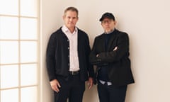 two men pose for a photo in a white room