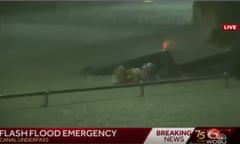 A newscast screengrab of a man holding another man up in high floodwaters