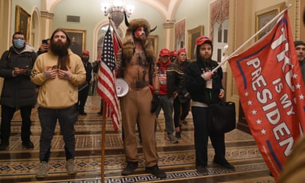 group of people with flags, one of them wearing a fur headdress