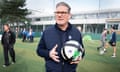 Starmer holders a football on a school pitch.