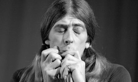 John Mayall with long hair playing harmonica