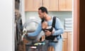 A black father with son in baby carrier doing laundry.