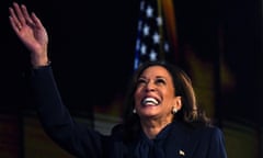 A smiling Kamala Harris raises her hand.