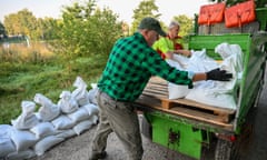 Two men unloading sandbags from the back of a small truck