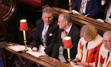 Keir Starmer speaks to Ed Davey, seated next to him, in wooden pews next to a woman and man in ermine capes at the coronation of King Charles