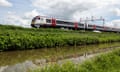 A train running on a green verge alongside a canal