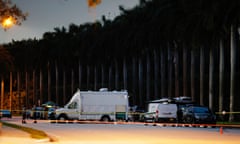 police cars and vans in front of trees at dusk