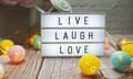 Live Laugh Love text on lightbox on wooden background