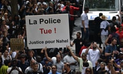 A crowd of protesters in Paris, with some holding a sign bearing the words "The police kill' and "Justice for Nahel".