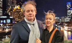 A man and woman standing outdoors in an urban city at nighttime.