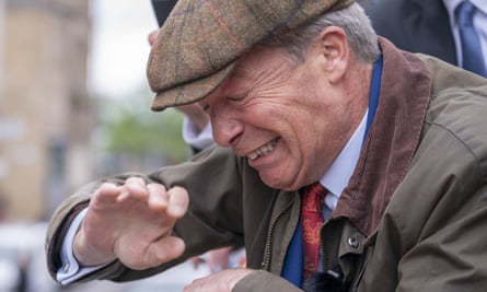 Nigel Farage reacts as something is thrown towards him: he is raising a hand to his face and grimacing with his eyes shut