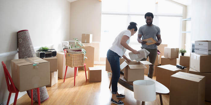 A couple unpacks boxes in their living room