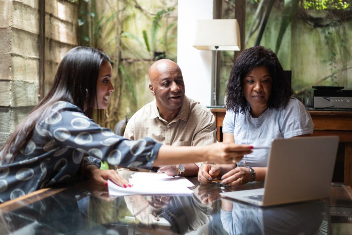 A young female mortgage broker shows a middle-aged couple loan options on a laptop