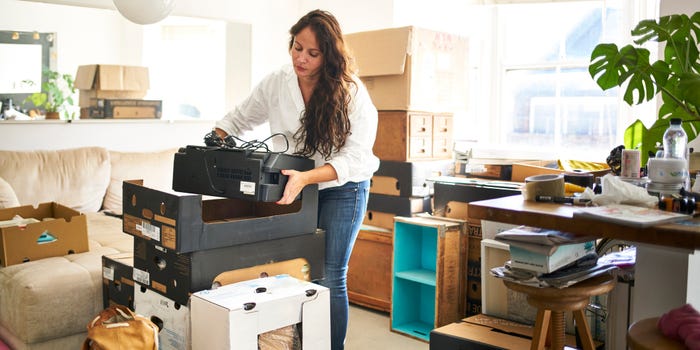 A young woman packs up boxes in her living room.