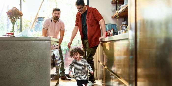 A couple chases their child around the kitchen