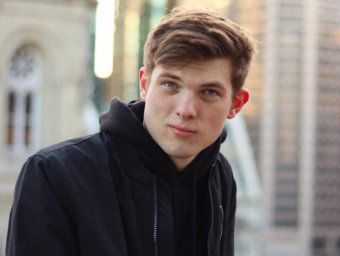 Nate O'Brien wearing a black hoodie while posing in front of an old-looking building.