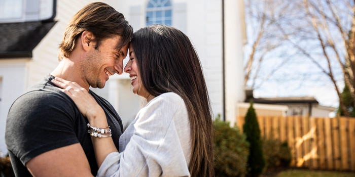 Husband and wife embrace in front of their home