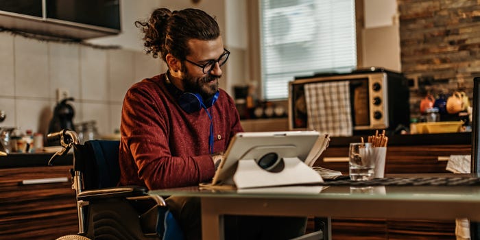 A photo of a man in a wheelchair sitting at a kitchen table