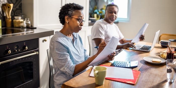 A couple sitting at their kitchen table looks over documents.