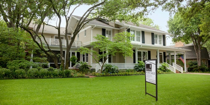 A beige, colonial-style house whose sellers have received homebuyer loved letters, with a "for sale" sign in the front yard