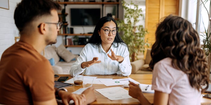 A photo of a financial adviser meeting with a young couple at home.