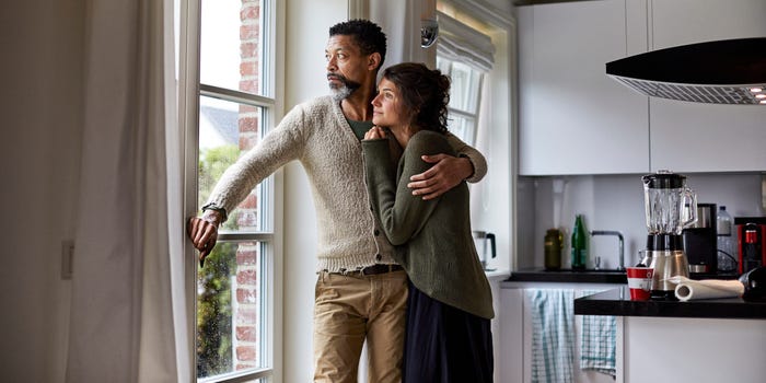 A man holds a woman as they both look out the window