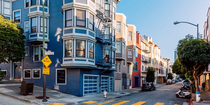 City street lined with colorful, Victorian-style apartments