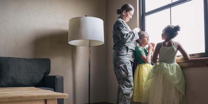 A mom in military uniform with a VA loan on her home does her two daughters' hair