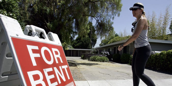 A woman walks by a "for rent" sign