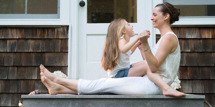 mother and daughter sit in front of the front door of their home