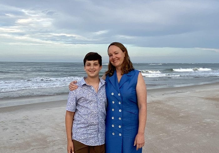 Ashley Archambault and her son standing on a beach together and smiling.