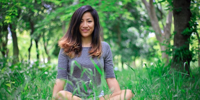 Katherine Fan sits in a field of green grass