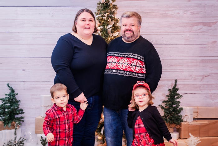 A mom, dad, and two young children pose for a family Christmas photo.