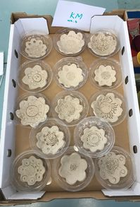 Kindergarten clay bowls using different sized flower shaped cookie cutters and sat in a mould to dry curved.