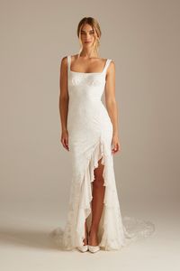 Carmen is a vision of timeless notes. Silk chiffon ruffles reference a vintage charm, weaving in references of texture with floral ivory lace. This asymmetric lace wedding dress is accented with a defined square neckline and thick straps. Carmen's details are poetic and deeply romantic.