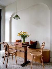 The kitchen counters and integrated sink are honed, locally quarried soapstone. The cabinetry was painted blue-black to match, and the island is a contrasting white oak. The white zellige floors were laid in a pattern referential to the parquet flooring in the living room. The breakfast area includes a built-in bench made from the same white oak as the island and a custom table designed for the space. New doors with transom windows were added, leading to a new steel deck in the rear yard.