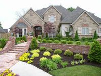 the stairs, brick pony wall, and shrub selections make this front landscaping beautiful