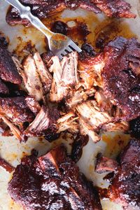 Shredded country-style pork ribs with a fork lying next to the ribs.