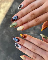 The nails display a colorful array of autumn-inspired shades with simple floral accents, ideal for the fall season.  🍂 Recreate this look yourself with our Korean Gel Nail Polish collection!  🍂 Credit: thehumbleroom_ on Instagram 🍂 almond nails, colorful nails, gel nails, brown nails, orange nails, yellow nails, green nails, blooming gel nails, floral nails, blooming nails, fall nails, autumn nails, september nails, summer to fall transition nails, fall nail designs, summer to fall transition nails, fall nail colors, Korean gel polish, nail trends, nail art, seasonal nails, elegant nails, nail polish, autumn colors, floral patterns, manicure ideas, gel nails, Instagram nails