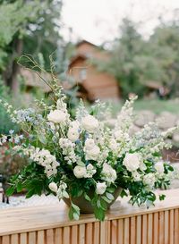 White rose, blue delphinium, white delphinium, white ranunculus, white anemone, white larkspur, white lysimachia bar centerpiece