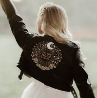 Introducing our stunning black cropped leather bride jacket - add a touch of celestial magic on your special day.  This jacket features exquisite moon and star zodiac embroidery, adding a celestial allure to your bridal ensemble. The cropped design offers a modern and fashionable twist, making it the perfect bridal cover-up for those looking to make a bold and unique statement. Whether you're planning a celestial-themed wedding or simply love astrology, our custom embroidered celestial bride jac