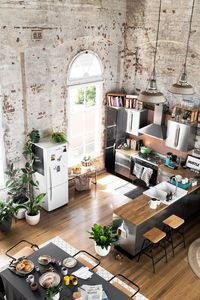 Converted warehouse makes for a stunning loft apartment. Exposed brick walls are soften with loads of indoor plants and timber furniture. Industrial style kitchen.