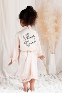 Satin lace flower girl robes make the perfect gift for the little girls in your bridal party! Soft polyester satin robes are printed with “Flower Girl” in your choice of gold foil, rose gold foil, silver foil, or black. Each robe comes with a matching belt for the outside. NO RETURNS OR EXCHANGES ON SHIRTS/CLOTHING ITEMS. Text Color Options Size: One size fits most girls ages 3-6 Length: 29" Chest Width (Shoulder to Shoulder): 13"  Material: 100% Satin Polyester CARE INSTRUCTIONS: Hand wash only, hang dry, DO NOT BLEACH. Iron/Steam on low heat only.