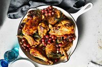 Angie Mar's Pan-Roasted Chicken with Grapes, Garlic, and Rosemary recipe brings together a crispy-skinned chicken and juicy grapes for a simple yet elegant dinner.