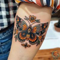 Dive into the charm of this beautifully designed butterfly tattoo with orange accents and floral elements. The bold lines and bright colors make it a cheerful choice for anyone's tattoo repertoire. Get inspired for your next butterfly tattoo at inktat2.com.