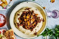 Topping hummus with meat is a way to pump up the protein and fat in the dish and make it closer to a meal than a side dish.