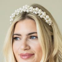 Odyssey is a striking and contemporary tiara with modern styling of clustered mix sized pearls. Perfect for brides looking for fresh styling and on trend inspiration.  Will compliment either romantic or modern gowns perfectly.  Also ideal for a modern look for a prom night. Set with ivory Natural Lustre Man Made Pearls and featuring a flexible headband design for comfort.     Plated in real Silver Measuring 3.3cm at the highest point Bestselling pearl tiara