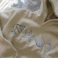 The Seashell Design Hoodie With Pockets brings the tranquility of the ocean to your everyday wardrobe. Crafted from 100% organic cotton, this hoodie offers a soft and comfortable fit, while the hand-embroidered seashell designs add a feel of artistic flair. It's perfect for those who appreciate fun, nature-inspired designs with a cozy feel. Features: Material: Made from 100% organic cotton, providing a soft and comfortable feel. Design: Features hand-embroidered seashells, adding an artisanal fe