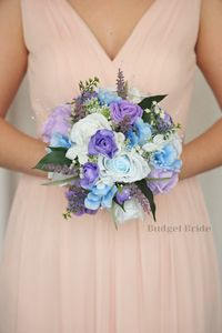 This lovely assortment of light blue and lavender is bound to turn heads on your wedding day. This lovely cascading brides’ bouquet from the is an absolutely breathtaking arrangement for any bride to be, in any season. Light blue and lavender fronds complete the look and add a delicate realism to this beautiful bouquet. This bouquet is 10” wide, 18” long, and is crafted by our in-house florists without using a foam base to anchor the flowers to the bouquet. Instead, we wire our bouquets by hand